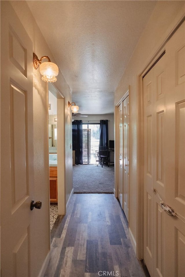 hallway with dark hardwood / wood-style flooring and a textured ceiling