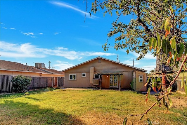 back of property with a lawn and central AC