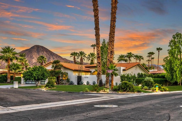 view of front of house with a mountain view and a lawn