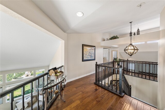 corridor featuring a notable chandelier, dark hardwood / wood-style flooring, and lofted ceiling