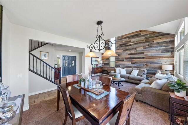 dining space featuring wooden walls and an inviting chandelier