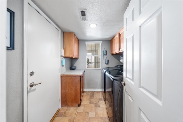 laundry area featuring cabinets, a textured ceiling, and washing machine and dryer