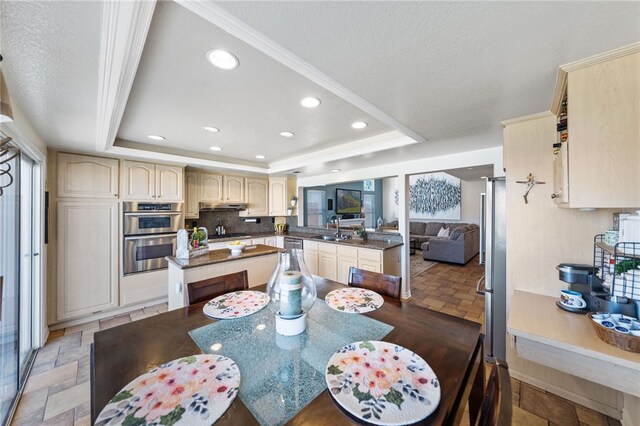 dining room featuring a tray ceiling, sink, a textured ceiling, and ornamental molding