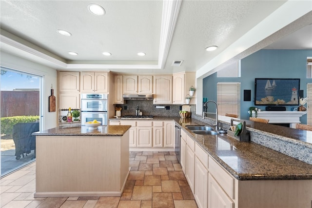 kitchen featuring a raised ceiling, decorative backsplash, sink, and dark stone counters