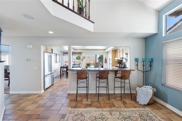 kitchen with a breakfast bar, stainless steel fridge, and kitchen peninsula