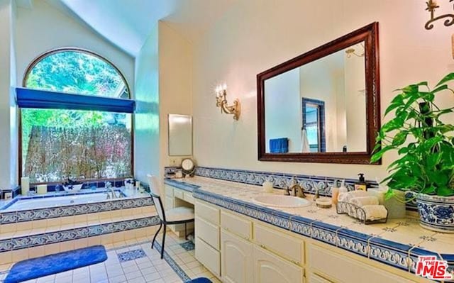 bathroom featuring lofted ceiling, tiled tub, vanity, and tile patterned floors