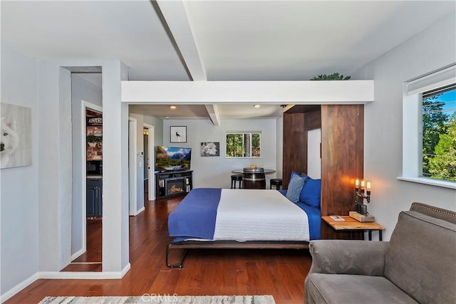 bedroom with a fireplace, beam ceiling, and wood-type flooring