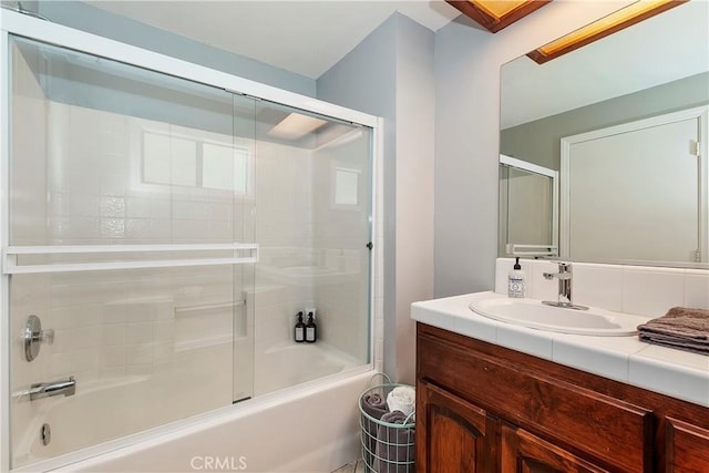 bathroom featuring a skylight, enclosed tub / shower combo, and vanity