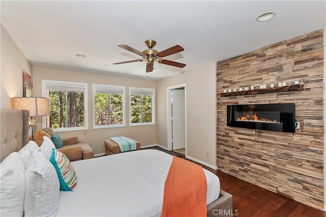 bedroom with ceiling fan, dark hardwood / wood-style flooring, and a fireplace