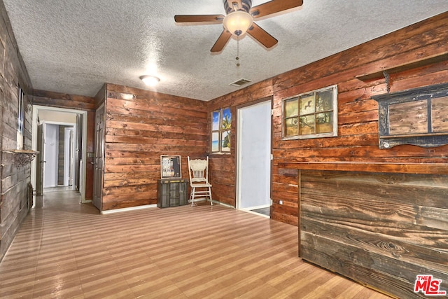 unfurnished living room featuring a textured ceiling, wood walls, and hardwood / wood-style flooring