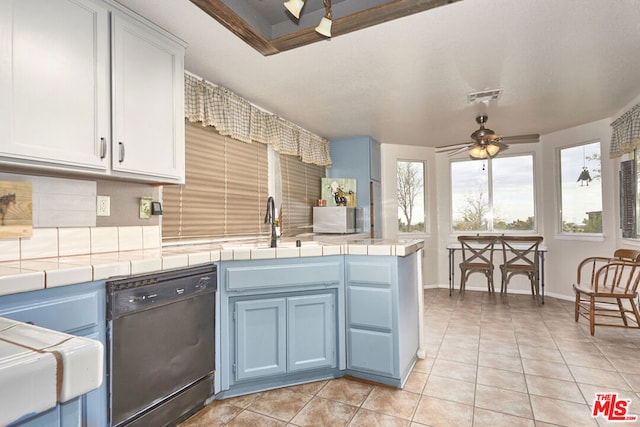 kitchen featuring blue cabinets, ceiling fan, light tile patterned floors, tile counters, and black dishwasher