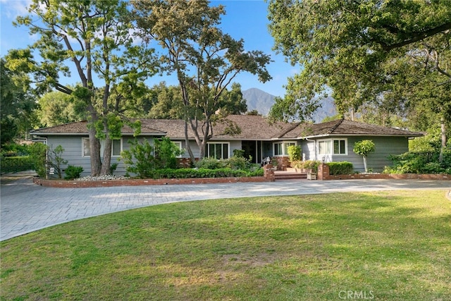 ranch-style home featuring a mountain view and a front lawn