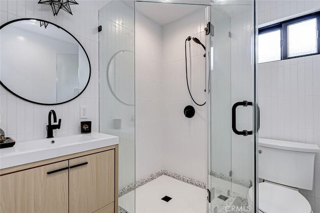 bathroom with a shower with shower door, tile walls, toilet, and vanity