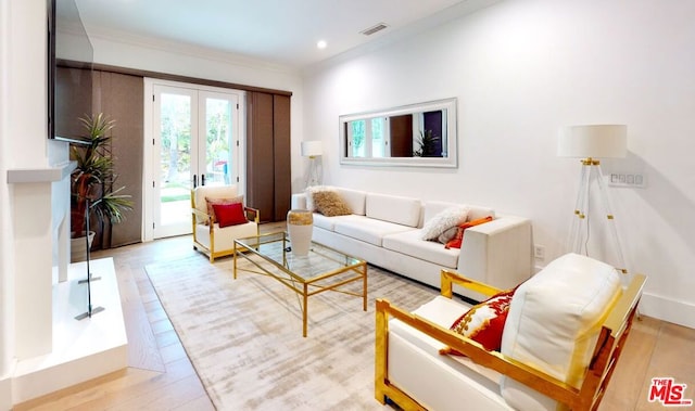 living room with ornamental molding, light wood-type flooring, and french doors