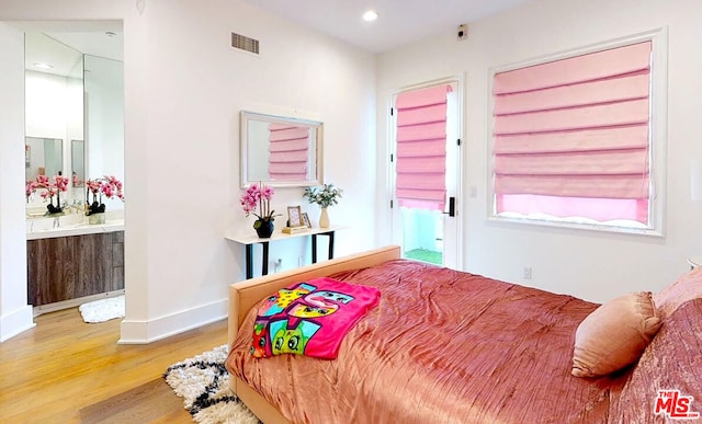 bedroom with ensuite bath and hardwood / wood-style floors