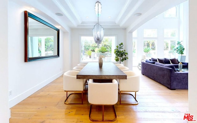 dining room featuring a notable chandelier, light hardwood / wood-style flooring, crown molding, and a raised ceiling