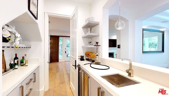 kitchen with wine cooler, pendant lighting, light wood-type flooring, crown molding, and sink