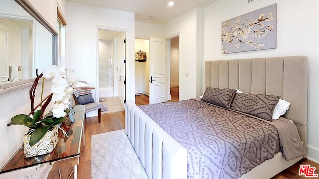 bedroom featuring light wood-type flooring and connected bathroom