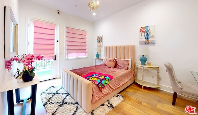 bedroom featuring a notable chandelier, access to exterior, and hardwood / wood-style flooring