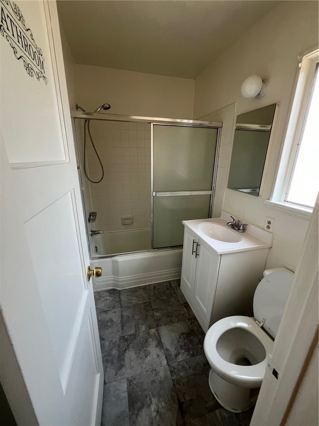 full bathroom featuring combined bath / shower with glass door, vanity, and toilet