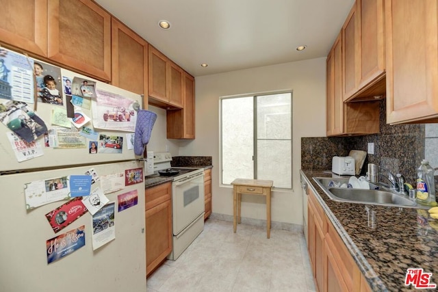 kitchen featuring tasteful backsplash, white appliances, sink, light tile patterned floors, and dark stone countertops