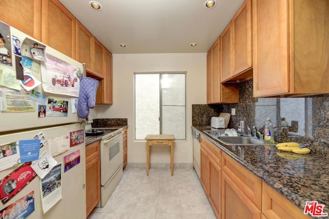 kitchen featuring sink, dark stone counters, white appliances, decorative backsplash, and light tile patterned floors