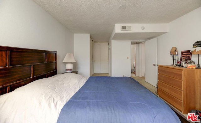 bedroom featuring a textured ceiling and light colored carpet