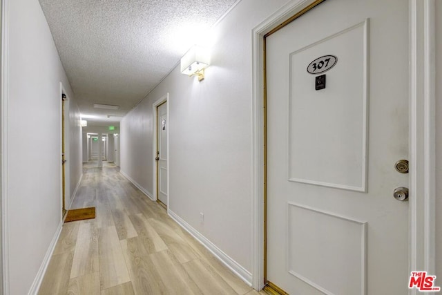 corridor featuring a textured ceiling and light wood-type flooring