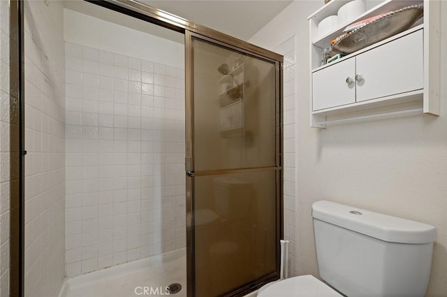 bathroom featuring toilet and a shower with shower door