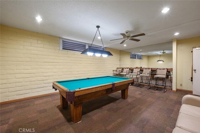 game room featuring brick wall, a textured ceiling, dark carpet, and billiards