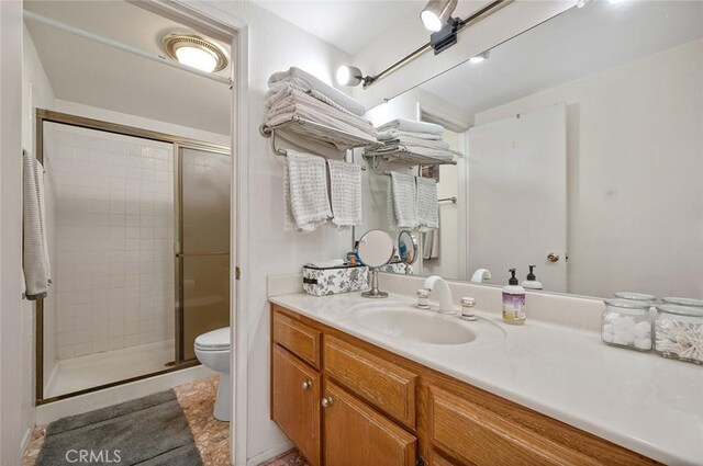 bathroom with vanity, toilet, and a shower with door