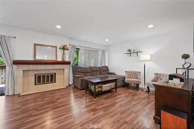 living room with a tile fireplace and hardwood / wood-style flooring