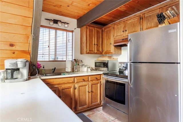 kitchen with appliances with stainless steel finishes, light tile patterned flooring, beamed ceiling, wooden ceiling, and range hood