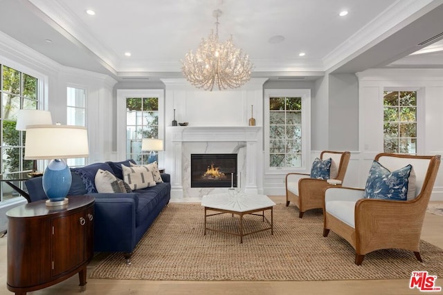 sitting room with light hardwood / wood-style floors, ornamental molding, and an inviting chandelier