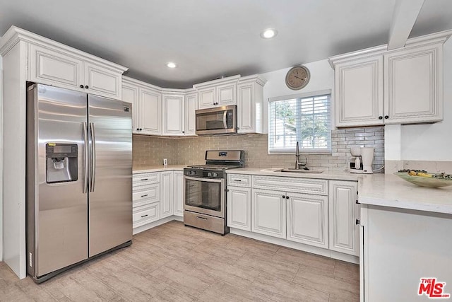 kitchen featuring backsplash, stainless steel appliances, white cabinetry, and sink