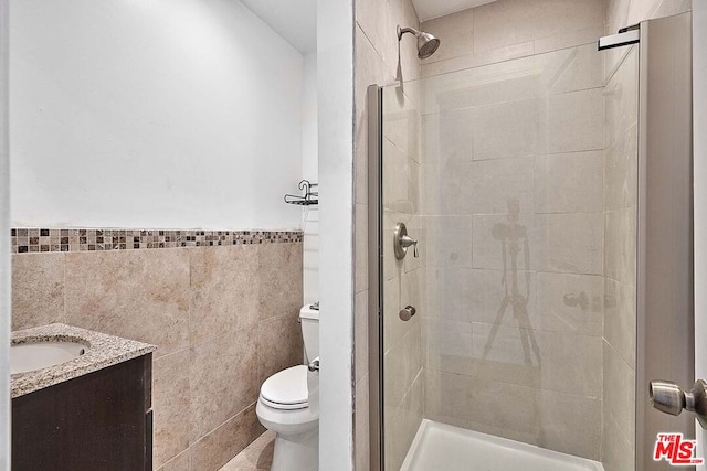 bathroom with tile walls, vanity, and toilet