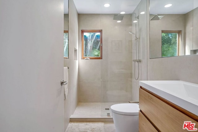 bathroom featuring a tile shower, vanity, and toilet