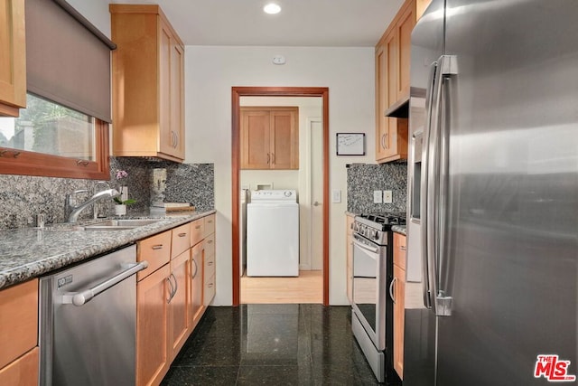 kitchen with appliances with stainless steel finishes, washer / clothes dryer, sink, and tasteful backsplash