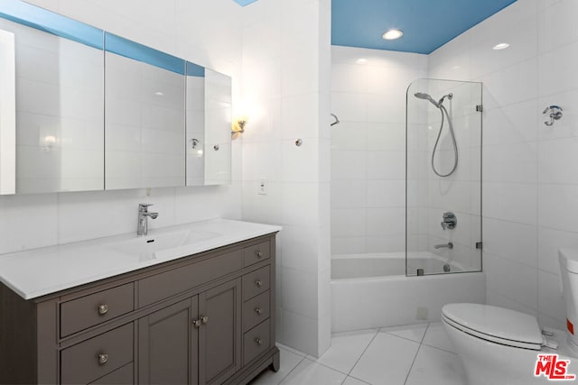 full bathroom with tiled shower / bath, vanity, toilet, tile walls, and tile patterned flooring