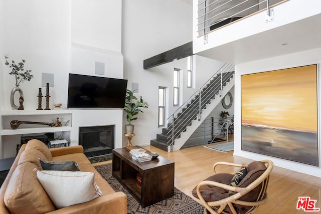 living room with a towering ceiling and wood-type flooring