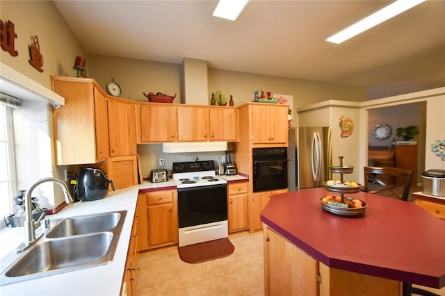 kitchen featuring electric stove, stainless steel refrigerator, a kitchen island, oven, and sink