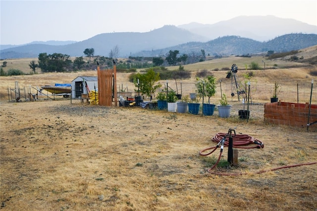 view of yard with a mountain view, a rural view, and an outbuilding