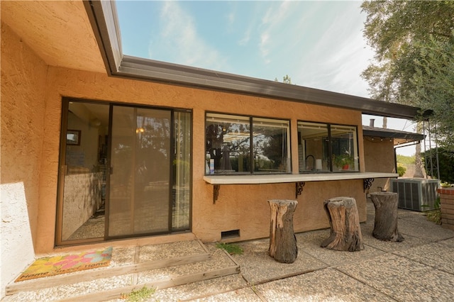 doorway to property with a patio and central AC unit