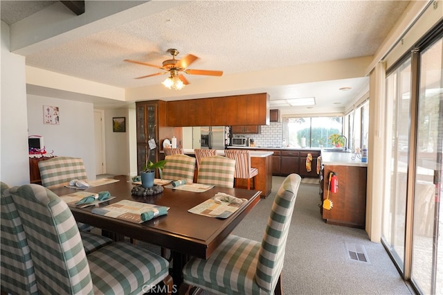 dining space with a textured ceiling, light colored carpet, and ceiling fan