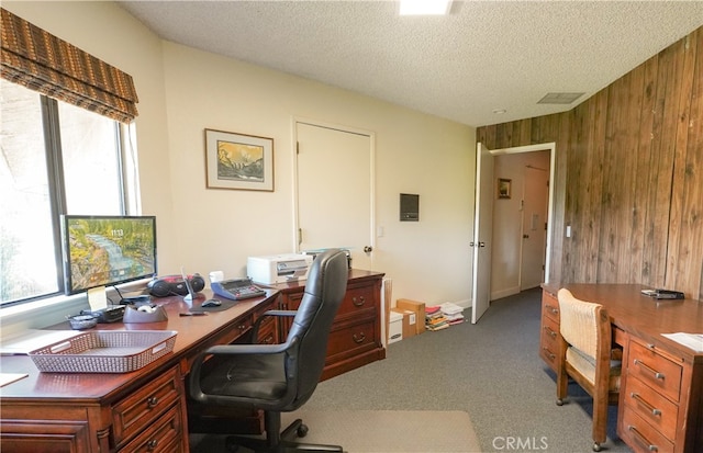 carpeted office with a textured ceiling and wooden walls