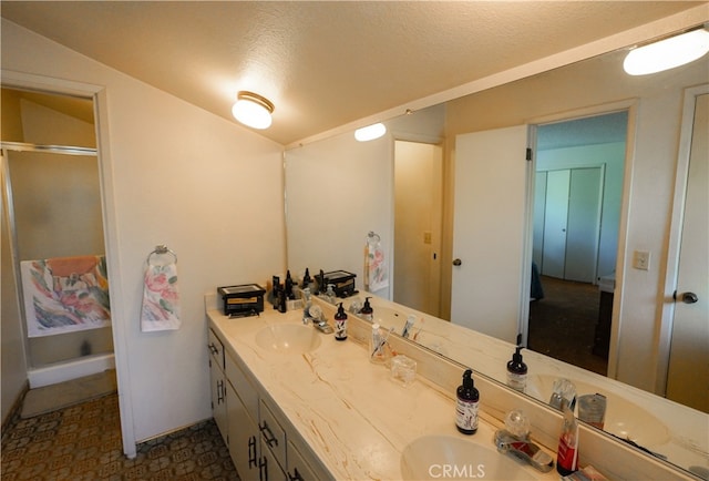 bathroom featuring a textured ceiling, vanity, and a shower with shower door