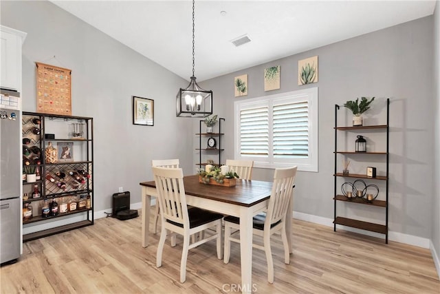 dining area featuring vaulted ceiling, a chandelier, and light wood-type flooring