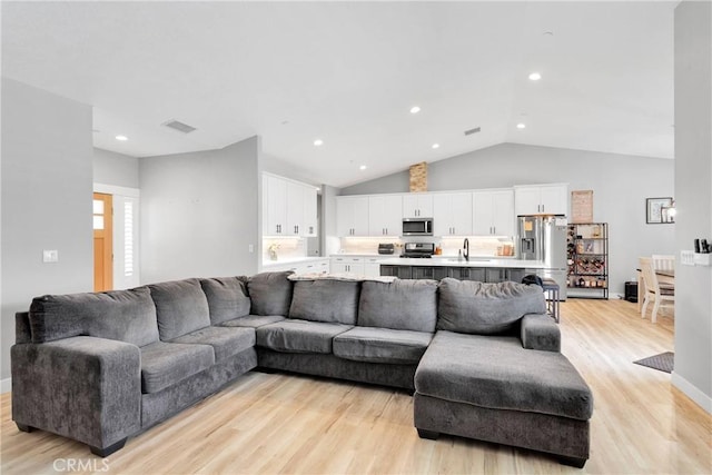 living room with light wood-type flooring and vaulted ceiling