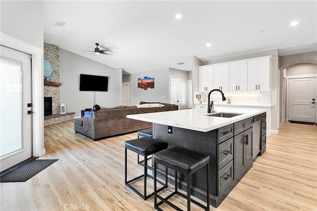 kitchen featuring light hardwood / wood-style floors, a center island with sink, ceiling fan, white cabinets, and sink