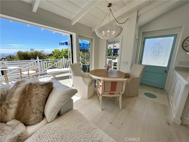 dining room with a chandelier, lofted ceiling with beams, and light wood-type flooring